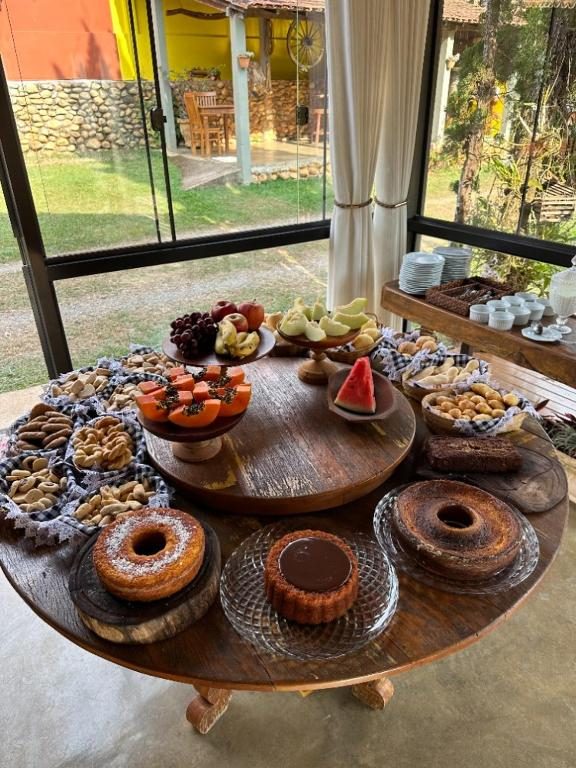 Mesa de café com bolos, frutas, pão de queijo e biscoitos
