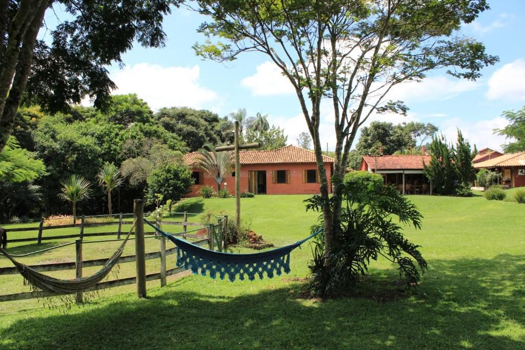 Gramado com redes armadas entre as árvores e as casas da pousada ao fundo